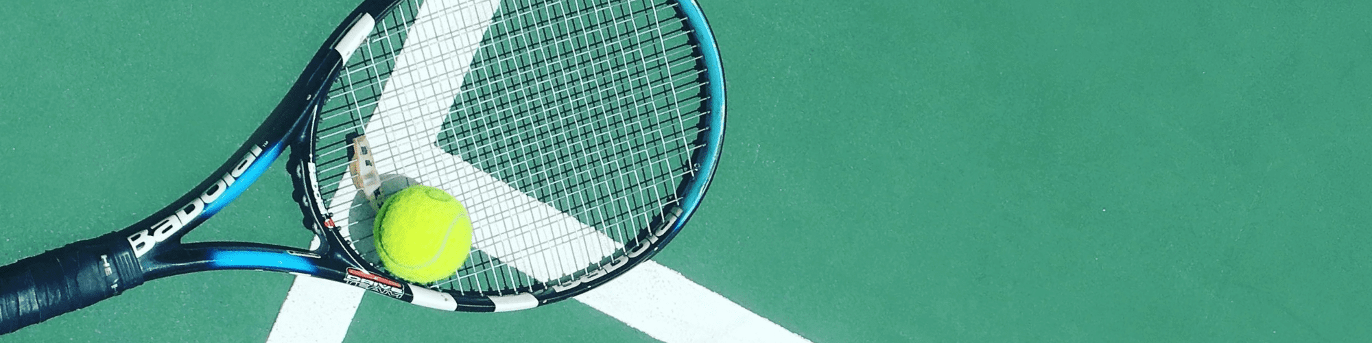 tennis racket with tennis ball on the ground of a tennis court