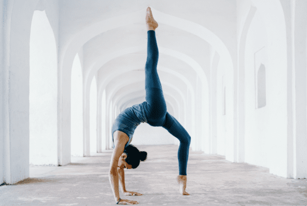woman doing a yoga exercise backbend in front of white archway