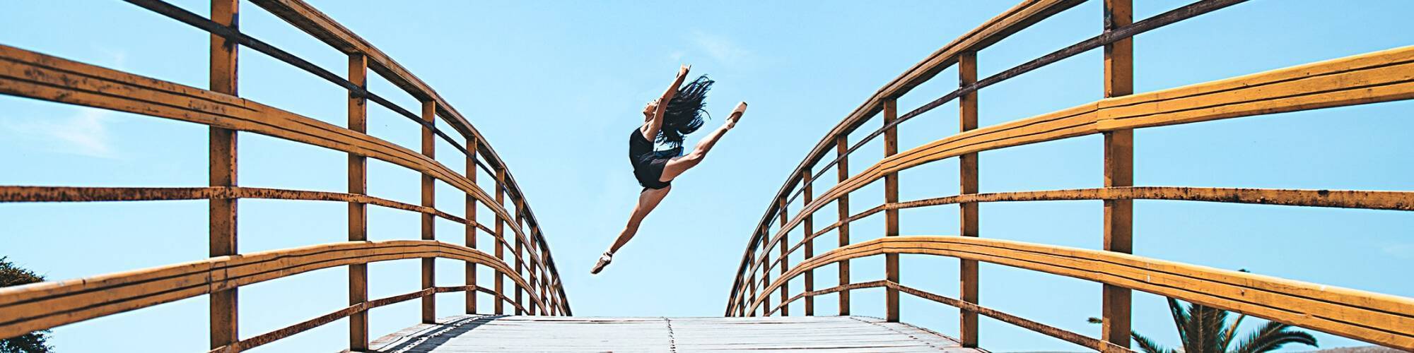 ballerina jumps in the distance with a wakling bridge in the foreground